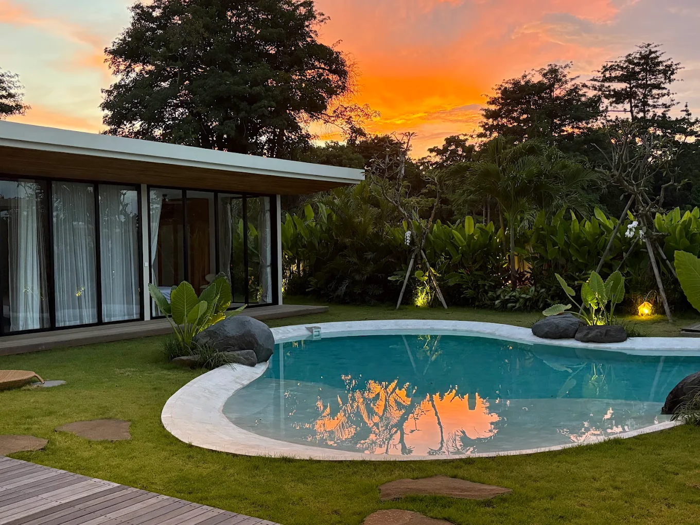 Freeform pool reflecting a sunset over the villa garden