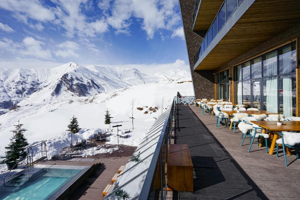Upper terrace with timber tables and chairs lined with white sheepskin throws, overlooking snowy peaks